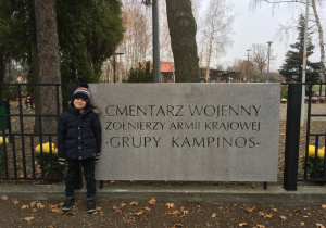 Na zdjęciu Wojtuś obok tablicy cmentarza wojennego